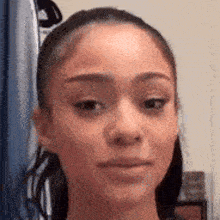 a close up of a woman 's face with a ponytail and a serious look on her face .