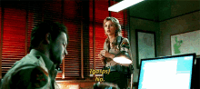 a woman in a sheriff 's uniform talks to a man in front of a computer screen