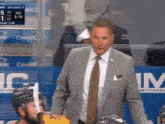 a man in a suit and tie stands in front of a scoreboard that says credit card