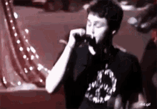 a young man is singing into a microphone on a stage .