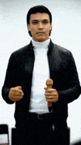 a man in a black jacket holds a microphone