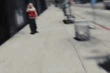 a woman in a red top is walking down a sidewalk