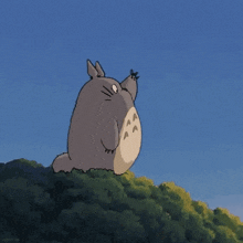 a cartoon totoro is standing on top of a hill with trees in the background