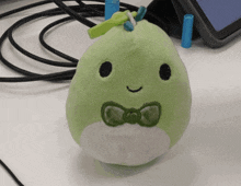 a green stuffed animal with a bow tie on its neck