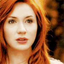 a close up of a woman 's face with long red hair