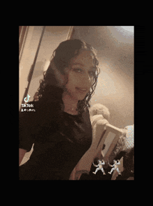 a girl with curly hair is taking a selfie in front of a mirror in a room .