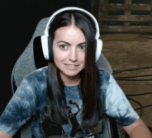 a woman wearing headphones and a tie dye shirt smiles for the camera