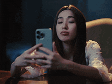 a woman is sitting at a table looking at her cell phone