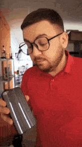 a man with glasses and a red shirt is holding a cell phone