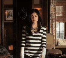 a woman wearing a black and white striped shirt stands in a room