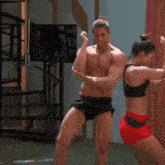 a man and a woman are standing next to each other in a gym