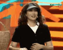 a woman wearing a visor and a black shirt is on a stage .