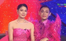 a woman in a pink dress is standing next to a man in a pink suit