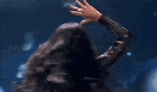a woman with long hair is dancing on a stage with her hands in the air .