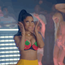 a woman in a bikini top and yellow skirt is standing in front of a crowd