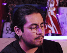 a man wearing glasses and earrings looks to the side