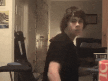 a man in a black shirt is standing in a room with a coca cola box in the background