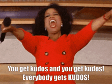 a woman in a red dress is holding a microphone and says " you get kudos and you get kudos