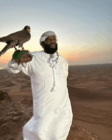 a man is holding a bird on his shoulder in the desert