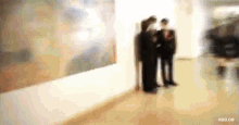a blurry picture of people looking at a painting with the url rbd.gif