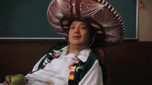 a man wearing a sombrero and a tie is holding an apple .