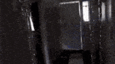 a person is standing in a doorway in a dark room with a reflection of a person in the window .
