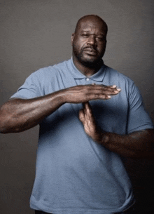 a man in a blue shirt is making a hand gesture with his hands .