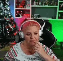 a woman wearing headphones sitting in front of a christmas tree .