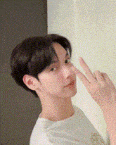 a young man is making a peace sign with his fingers .
