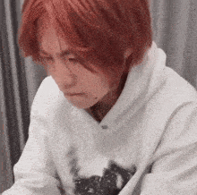 a man with red hair is wearing a white hoodie