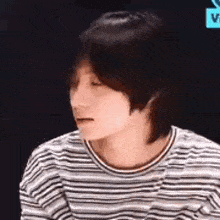 a close up of a person wearing a striped shirt and looking down .