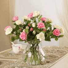 a vase of pink and white roses sits on a table