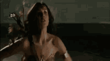 a woman in a wonder woman costume is standing in a dark room and looking at the camera .