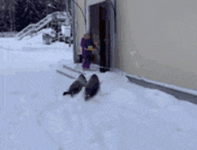 a person in a purple jacket is standing in the snow near a doorway