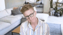 a man wearing glasses and a striped shirt looks at the camera