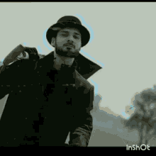 a man with a beard wearing a hat and holding a gun .