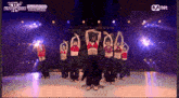 a group of women are dancing on a stage with the word mnet on the bottom left