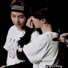 a man wearing a headband is touching another man 's face .