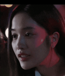 a close up of a woman 's face with a red light behind her ear