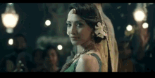 a woman in a green dress and veil looks at the camera