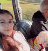 a woman is sitting in the back seat of a car holding a dog
