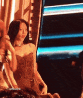 a woman in a corset is talking into a microphone with reflexlink written on the bottom right
