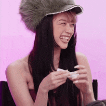 a woman wearing a fur hat is smiling and holding something in her hands
