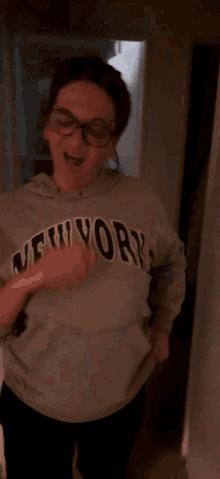 a woman wearing a new york sweatshirt is dancing in a hallway