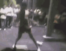 a blurry picture of a person walking down a street with a crowd in the background .