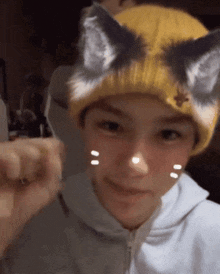 a young boy wearing a yellow beanie with cat ears on it