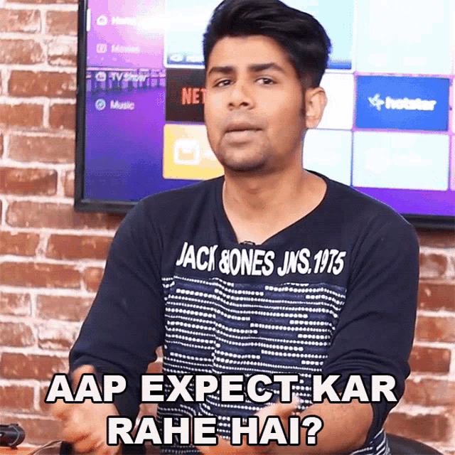 a man wearing a jack bones jns 1975 shirt is sitting in front of a television