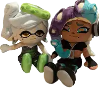 two stuffed dolls sitting next to each other on a white surface