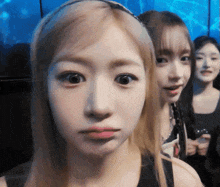 a close up of a woman 's face with two other girls behind her