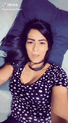 a woman in a polka dot shirt is laying on a bed with a pillow and a tiktok watermark
